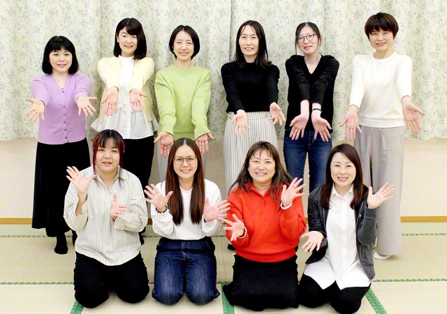 麗しいスクラムで前進する見沼共戦本部の女性部。ヤング白ゆり世代の創春リーダーらがカメラに（3月、見沼文化会館で）