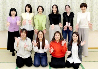 麗しいスクラムで前進する見沼共戦本部の女性部。ヤング白ゆり世代の創春リーダーらがカメラに（3月、見沼文化会館で）