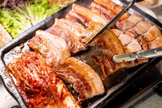 厚切りサムギョプサル（1人前2068円）。※写真は2人前。注文は2人前から。青唐辛子やにんにく、自家製みそ、ねぎあえなどの薬味も、サンチュもおかわり無料サービス。薬味と一緒にサンチュで肉を巻いて食べよう