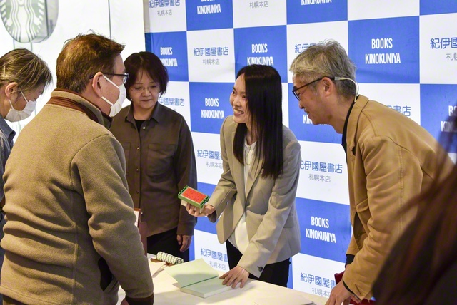 ブックトークで、書籍に記念のスタンプを押す安達さん（右から2人目、4月11日、紀伊國屋書店札幌本店で）