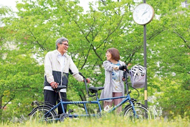 病を患って15年になる平松さん㊧。失明した今は、妻の真実さん㊨と共に、2人乗りのタンデム自転車のペダルをこぎ、励ましと対話拡大に駆ける。世に残る仕事をしたいとの願いもかなった。障がい者をはじめ誰もが利用できるバリアフリー案内システム「えきペディア」事業のデザイン制作に携わった。2010年にはグッドデザイン賞等を受賞した