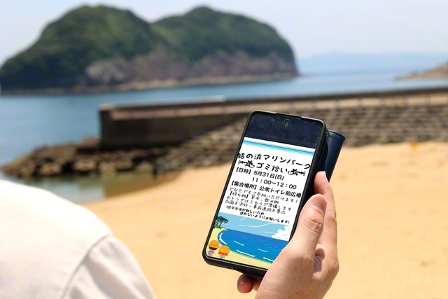 デジタルチラシを眺め砂浜に立つ（5月31日、諫早市内で）