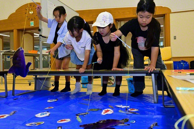 釣りゲームに興じる子どもたち。琵琶湖に生息する在来魚や外来魚を釣り上げ、裏に書かれた点数で競い合った