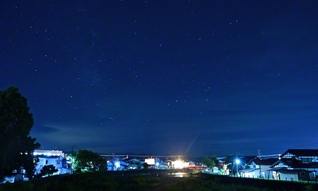 町の明かりと満天の星が同居する、羽後町の夜。川沿いに並ぶ家々の明かりが、まるで星々と呼応するように輝いていた
