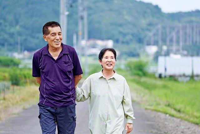 目の見えない石垣さん㊨は、いつも夫・秀雄さん（地区幹事）と共に歩く。「妻がこんなによく笑う人だと思ってなかった」と、その前向きな姿は地域を明るく照らしている。音で覚えた御書の一節が次々と口から出てくる中で、心に刻むのは「南無妙法蓮華経は師子吼のごとし、いかなる病さわりをなすべきや」（新1633・全1124）と語る